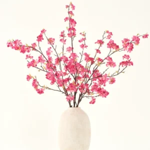 Der künstliche Blumenstrauß aus Seide, Kirschblüten-Fuchsia, 150 cm, besteht aus leuchtend fuchsiafarbenen Kirschblütenstielen mit grünen Blättern in einer schlichten weißen Vase, die vor einem hellen Hintergrund jedes Interieur ergänzt.