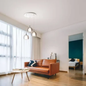 Bretagna Pendelleuchte 3-flammig über einem modernen Wohnzimmer mit Ledersofa