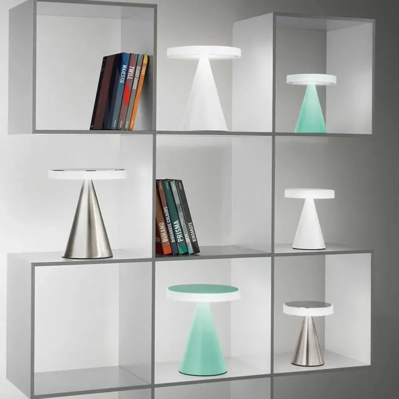 moderne LED Tischleuchte Neutra in einem stilvollen Regal mit Büchern und verschiedenen Leuchten.