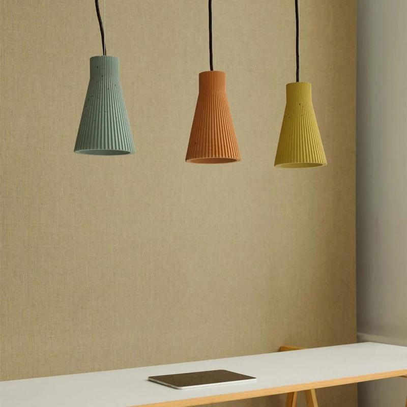 Gantlights S1 Beton Pendelleuchte geriffelt in verschiedenen Farben hängen über einem Tisch.