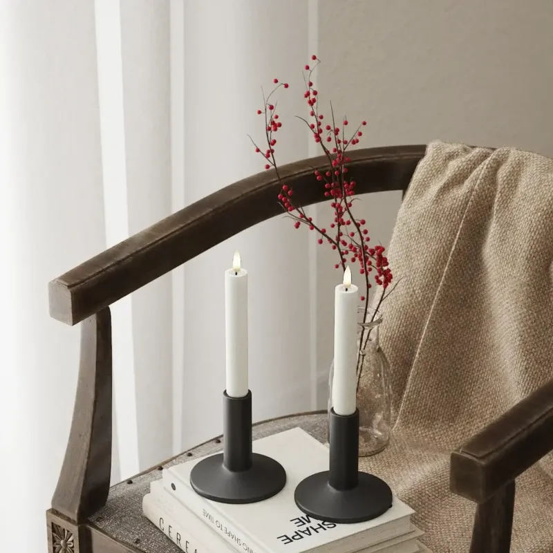 Zwei Nordic Flame LED Stabkerzen mit 3D-Flamme in schwarzen Haltern auf Stuhl, gemütliches Wohnambiente