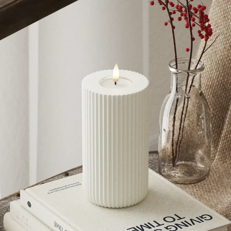 LED Stumpenkerze mit 3D-Flamme von Nordic Flame auf Buch, daneben Vase mit roten Beeren