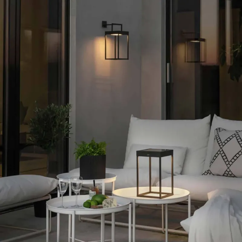 Portofino LED Solar Bodenleuchte IP54 in modernem Außenbereich mit stilvollem Tisch und gemütlicher Sitzgelegenheit.