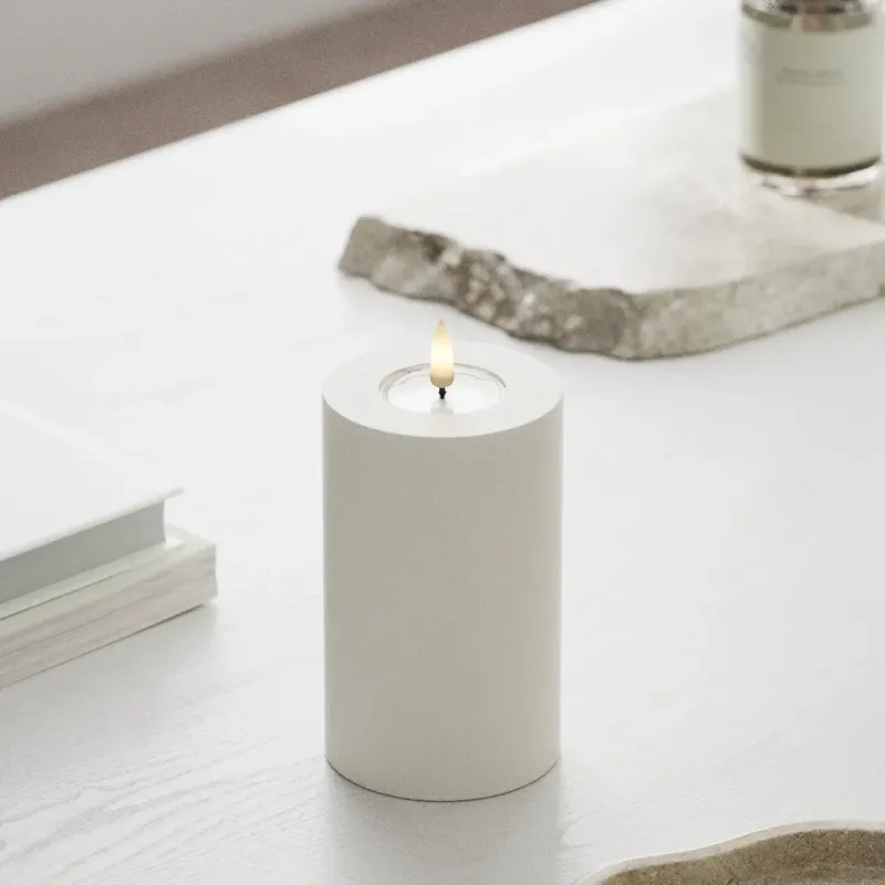 Weiße LED Stumpenkerze mit 3D-Flamme aus Echtwachs von Nordic Flame auf weißem Tisch