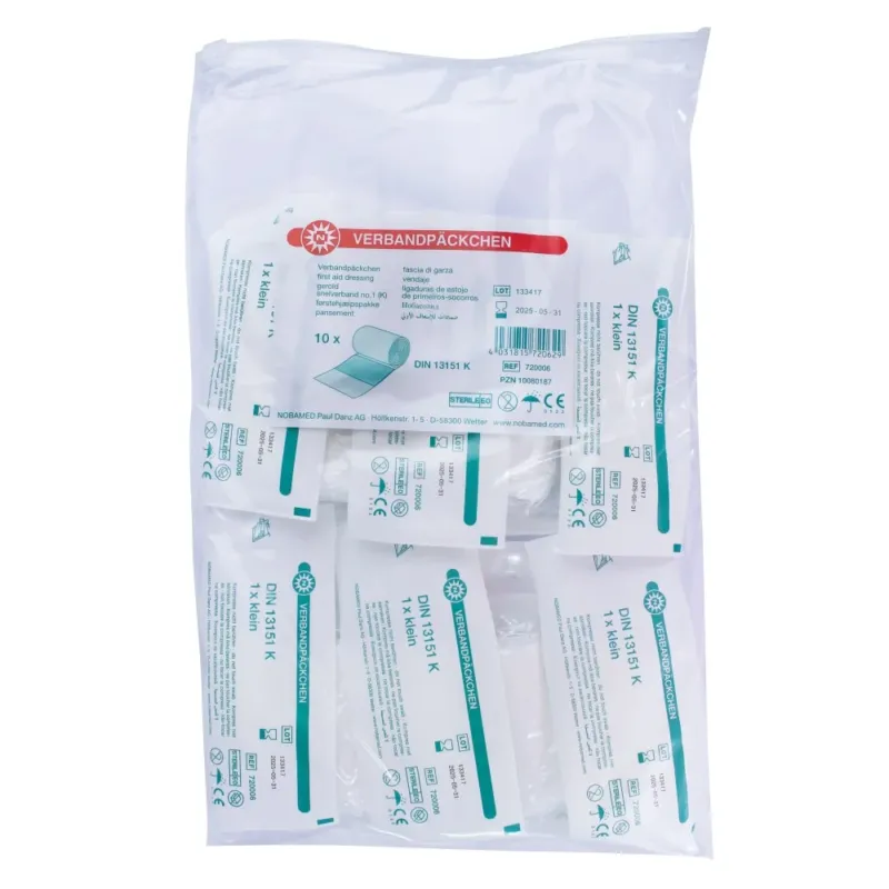 Kleinformatiges Noba Verbandpäckchen in einer transparenten Verpackung. Das Verbandpäckchen ist ordentlich gefaltet und vollständig sichtbar. Auf der Verpackung sind Informationen über den Inhalt und die Anwendung aufgedruckt. Die Farben der Verpackung sind hauptsächlich Weiß mit blauen und roten Akzenten. Im Hintergrund ist eine helle, neutrale Fläche zu sehen, die den Fokus auf das Produkt lenkt.