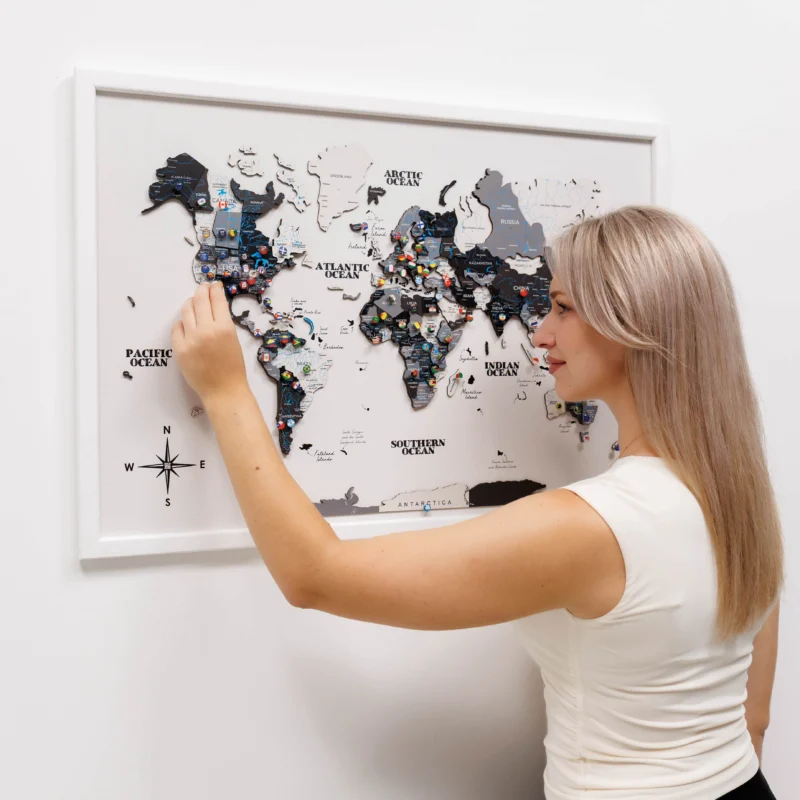 Woman interacting with a world map poster on a white wall