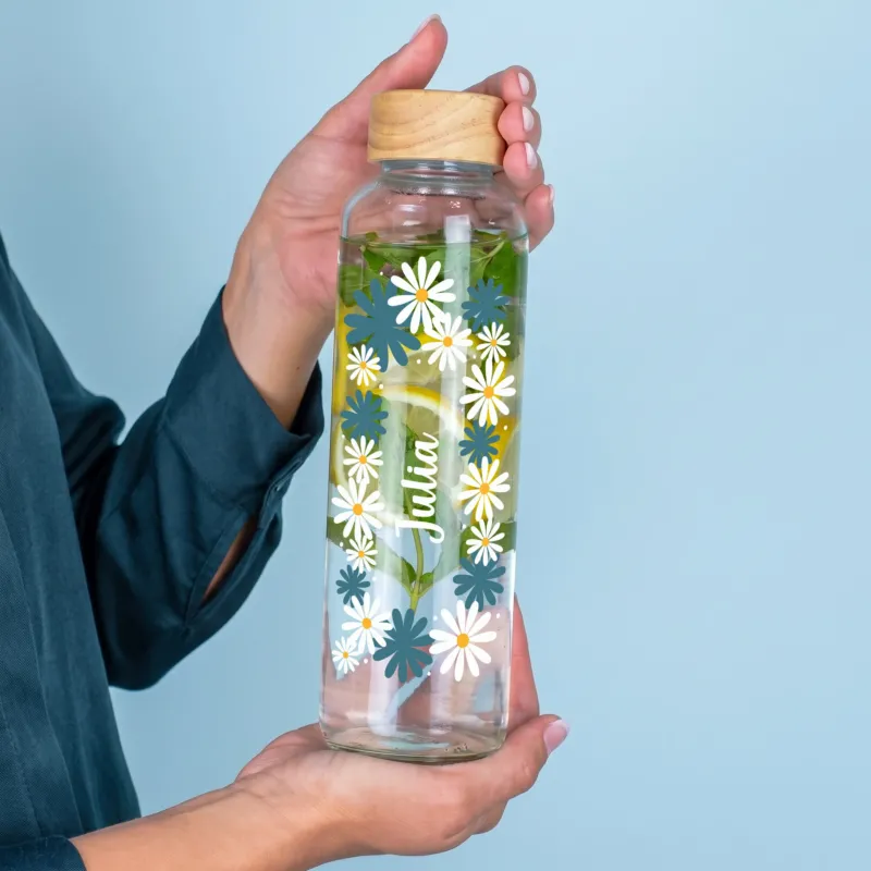 Personalisierte 600 ml Trinkflasche aus recyceltem Glas mit Wunschnamen und floralem Motiv in der Hand