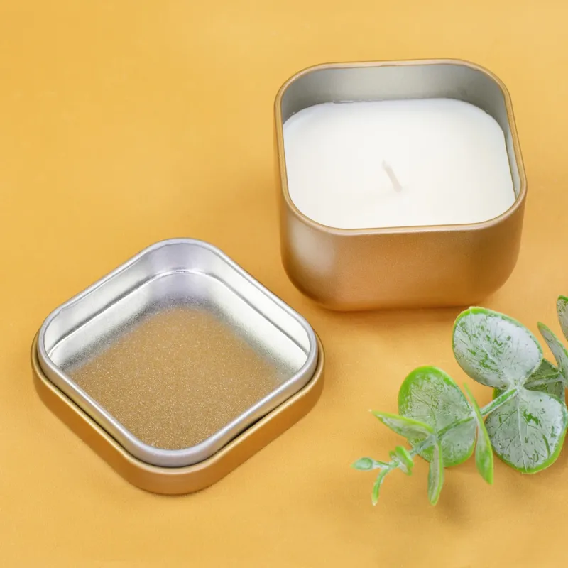Geöffnete goldene Duftkerze mit Vanilleduft, losem Deckel und grüner Dekoration auf gelbem Hintergrund