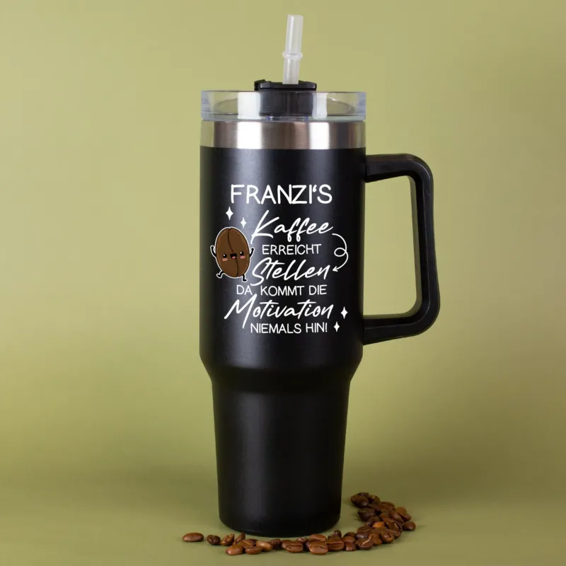 Thermobecher in Schwarz mit Kaffee-Spruch und Name vor grünem Hintergrund mit Kaffeebohnen dekoriert