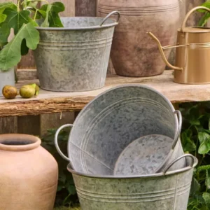 Metalltöpfe konisch im 3er-Set mit Henkeln dekorativ im Garten arrangiert.