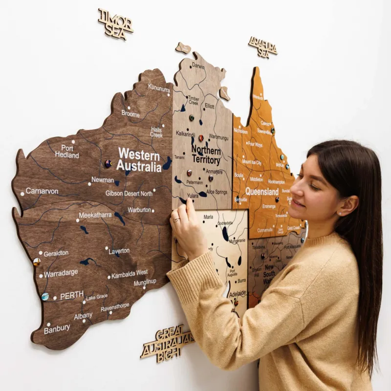 Woman interacting with a wooden map of Australia on a white background